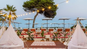 A terrace with seating and a canopy, overlooking a pool area. - Hotel Riomar Ibiza, A Tribute Portfolio Hotel (Santa Eulalia del Rio)