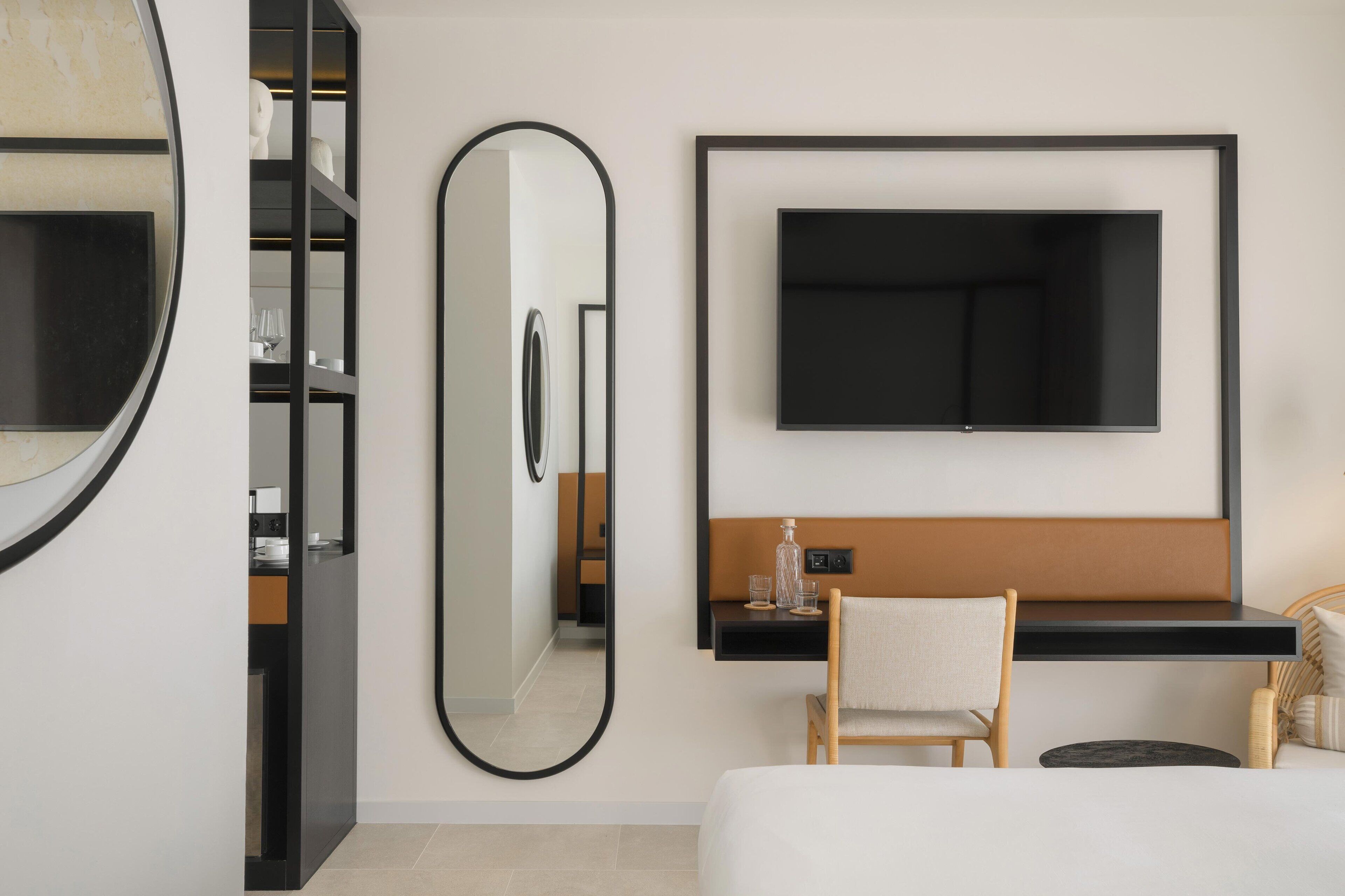 Een moderne hotelkamer met een groot bed, een nachtkastje, een stoel, een aan de muur bevestigde televisie en een grote spiegel.