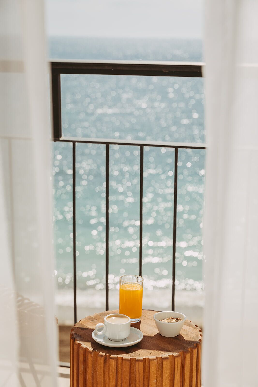 Un balcón con una mesa lista para el desayuno, que incluye una taza de café, un vaso de zumo de naranja y un tazón de cereales.