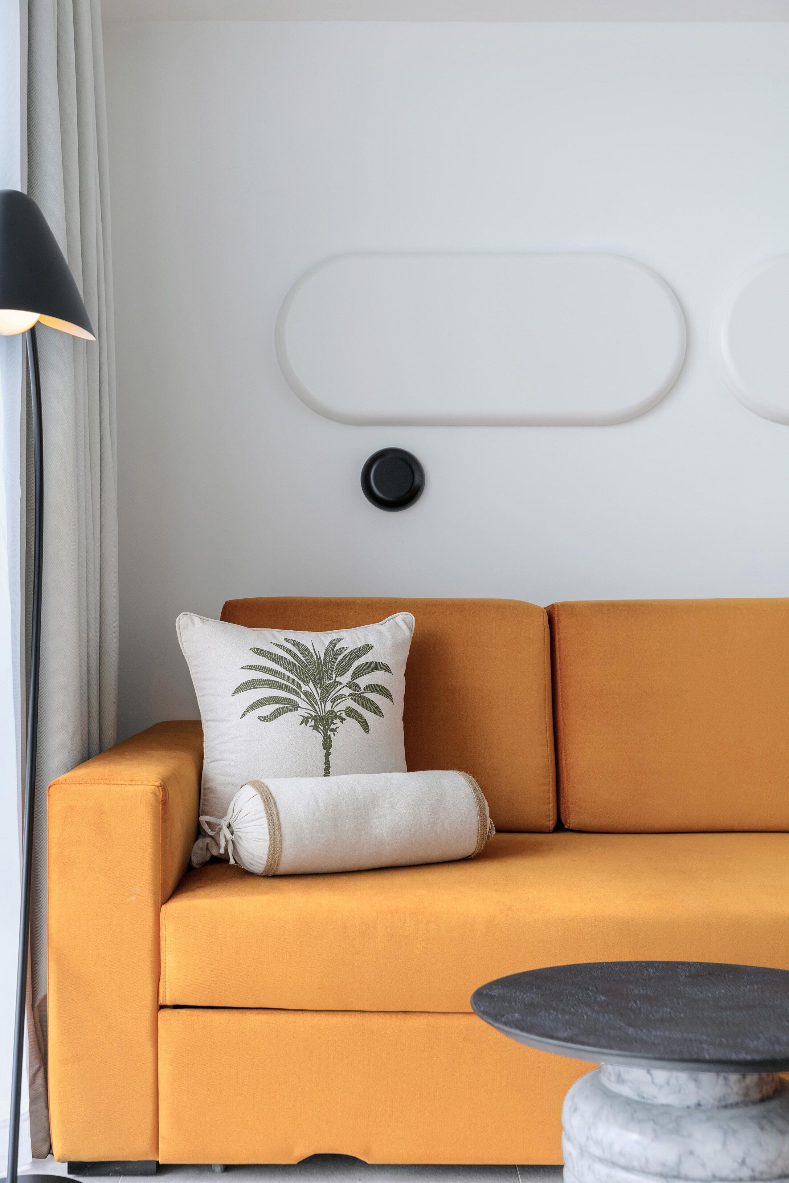 A modern living room with a mustard-colored sofa, a round marble coffee table, and a lamp.