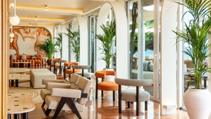 A modern lobby with seating areas, large windows, and indoor plants. - Hotel Riomar Ibiza, A Tribute Portfolio Hotel (Santa Eulalia del Rio)