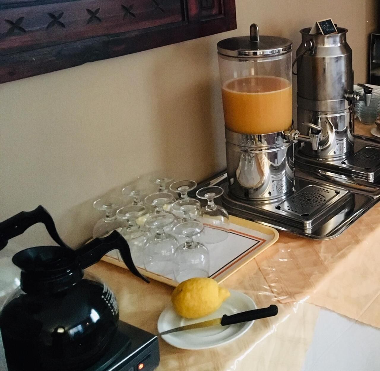 A coffee station with a coffee press, a glass carafe, and a lemon on a plate.