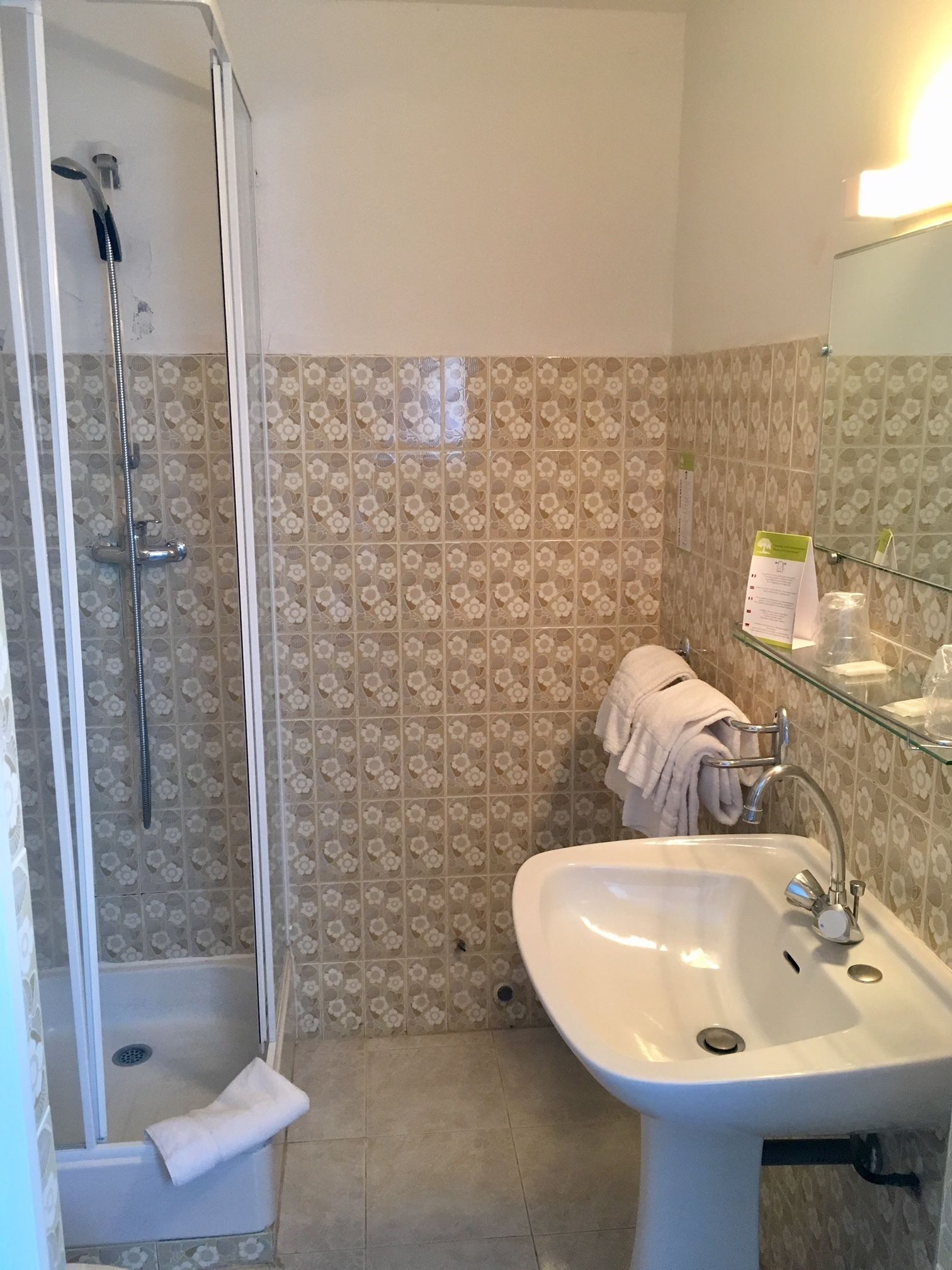 Un bagno con doccia, lavandino e pareti rivestite di piastrelle.