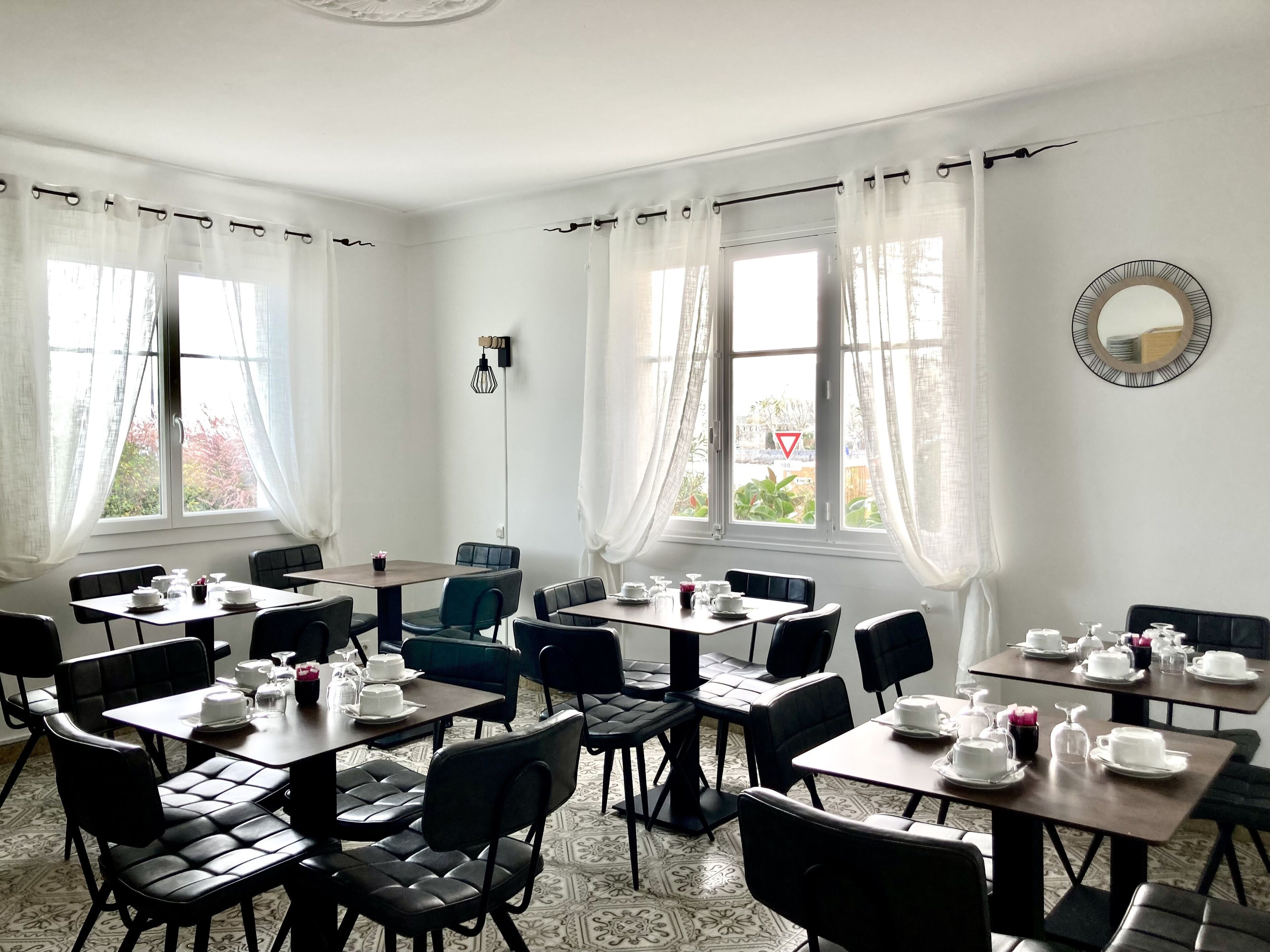 A dining area with tables set for tea service, featuring black leather chairs and white table settings.