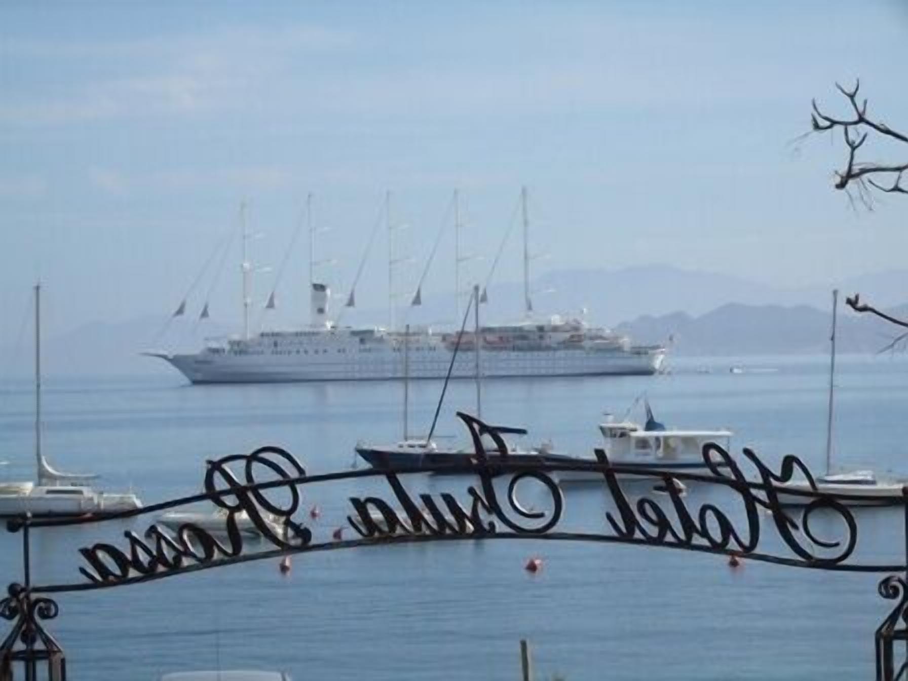 Ein großes Kreuzfahrtschiff liegt in einer Marina vor Anker, wo ein Schild "Plum Harbor" zeigt.
