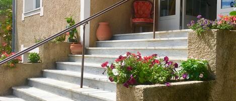A building with a stone facade, a set of outdoor stairs, and a red chair.