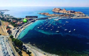 An aerial view of a coastal area with a marina, boats, and a rocky island.