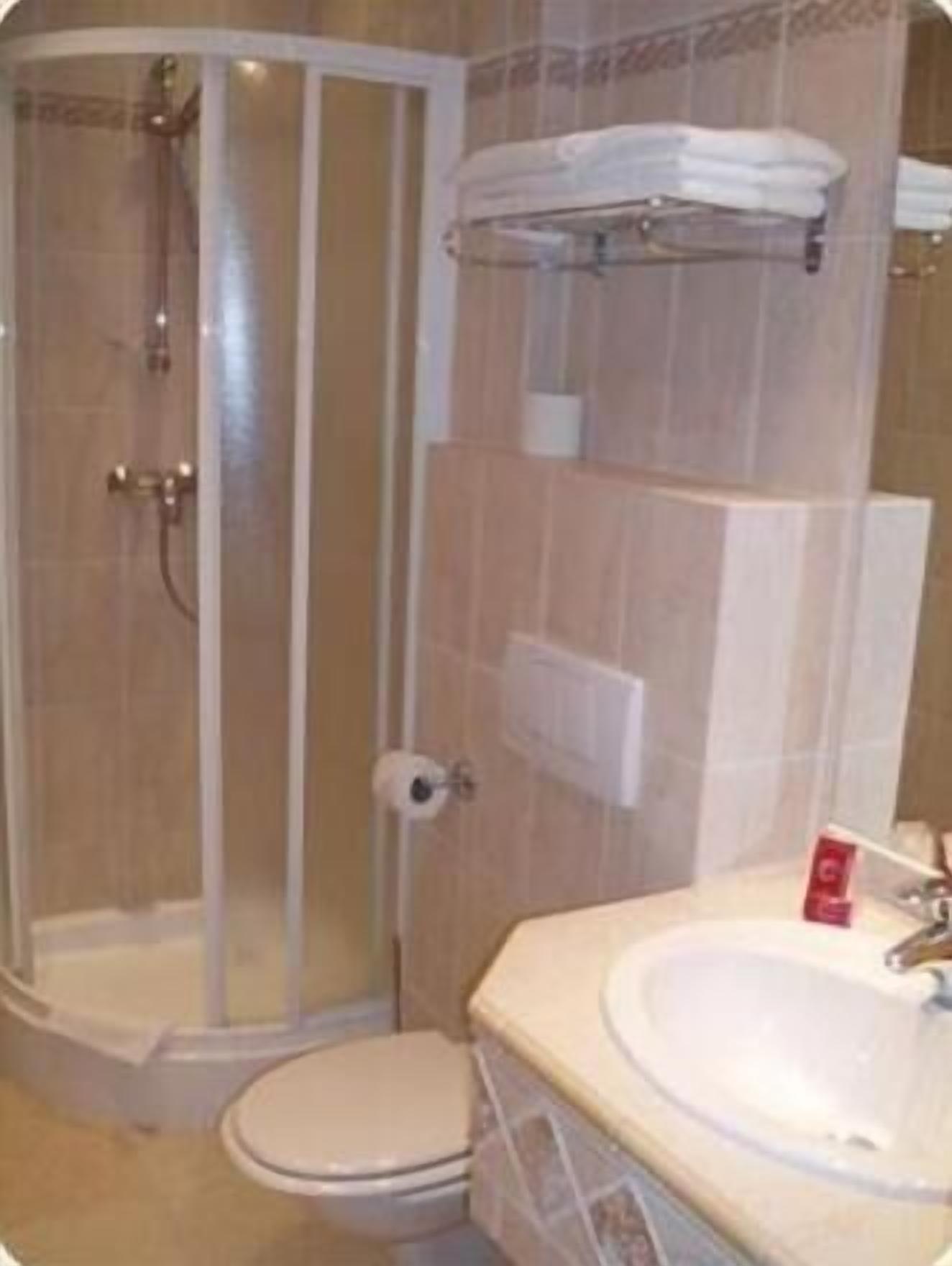 Un baño con ducha de vidrio, inodoro y lavamanos.