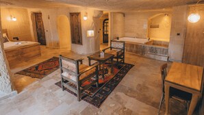 Una habitación rústica con una cama, una mesa de madera, una silla, una mesita con una lámpara, una alfombra y una bañera.