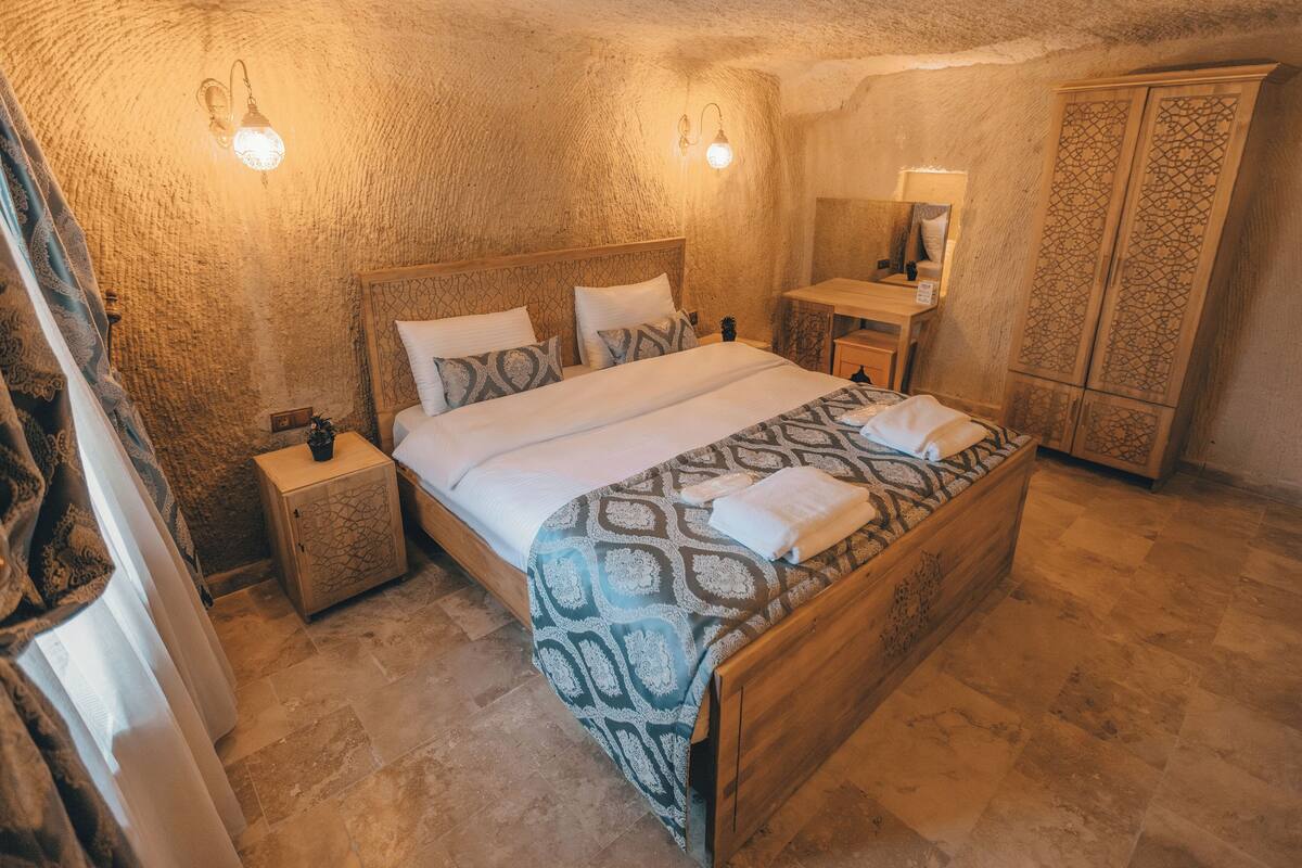 Un dormitorio con una cama de madera, una mesita de noche, un armario y un espejo.