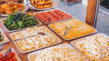 Un bufé con diferentes opciones de comida, incluyendo ensaladas, quesos y carnes.