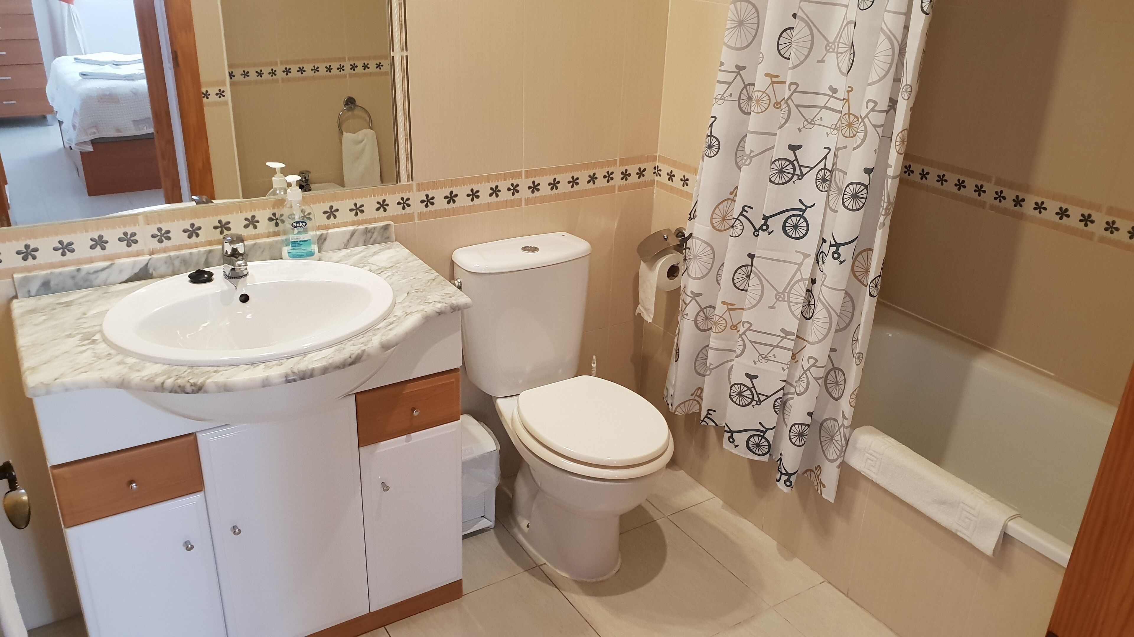 A bathroom with a white sink, toilet, and shower curtain with bicycle patterns.
