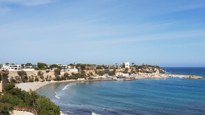 Una località costiera con edifici lungo la costa, una spiaggia e una vista limpida sul mare.