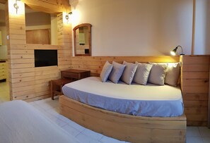 A wooden cabin-style bedroom with a bed, bedside tables, a mirror, and a built-in shelf. - Anemos Hotel (Kassandra)