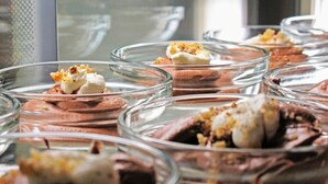A dessert display with chocolate mousse topped with whipped cream and nuts. - Anemos Hotel (Kassandra)