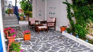 A stone-tiled patio with outdoor furniture, potted plants, and a staircase leading to an upper level. - Anemos Hotel (Kassandra)