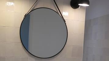 A bathroom with a white sink, a round mirror, and two wall-mounted lights.
