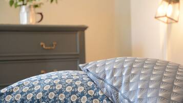 A bed with patterned pillows, a dresser, and a vase with flowers.