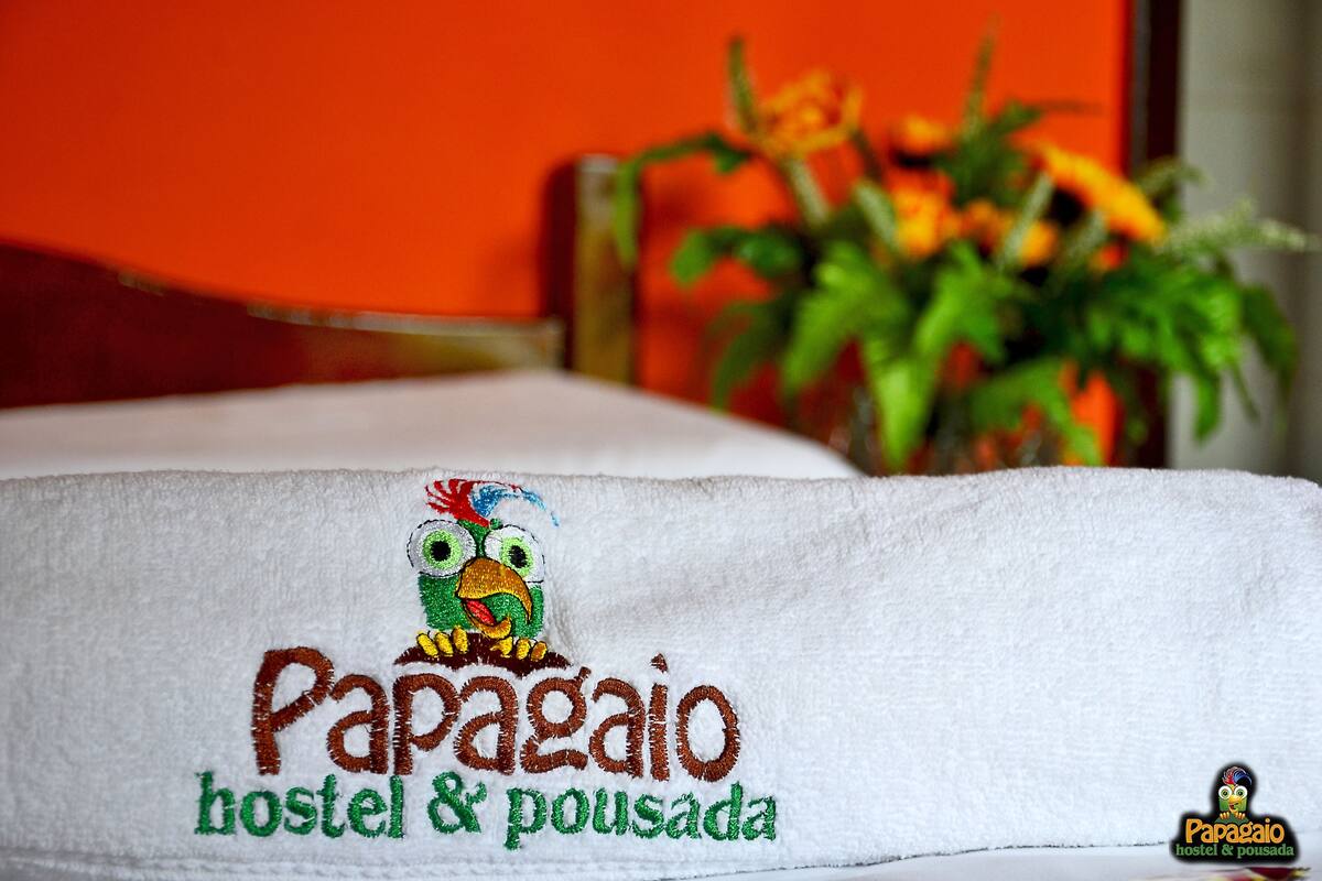 A towel with a colorful embroidered design and text reading "Papagayo hostel & pousada".