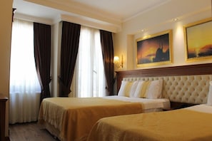 Habitació d'hotel amb dos llits, una finestra gran amb cortines i un quadre a la paret.