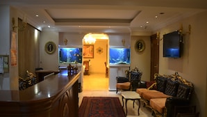 A spacious living area with a bar, two large aquariums, a television, and ornate furniture. - Hotel Blue Istanbul - Special class (Istanbul)