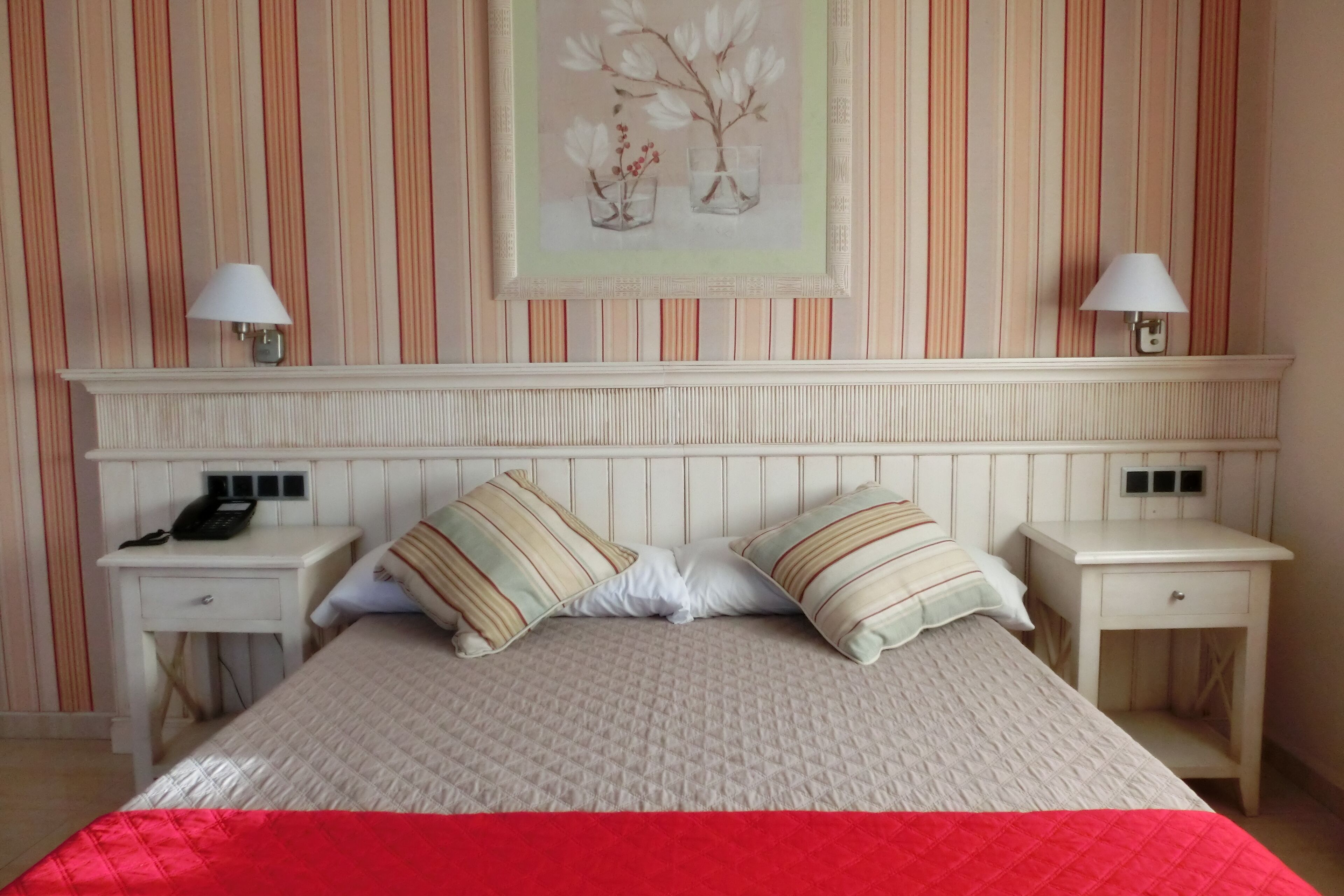 Une chambre d’hôtel bien rangée, avec un lit, des tables de chevet, des lampes et une œuvre d’art encadrée accrochée au mur.