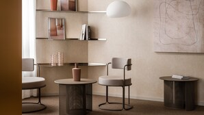 Un interior moderno con un diseño minimalista, que presenta un sofá, dos sillones, una mesa redonda, una estantería y un cuadro abstracto grande en la pared.