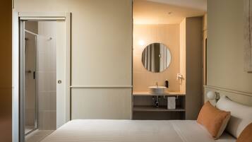 A hotel room with a bed, a bathroom with a sink, and a shower.