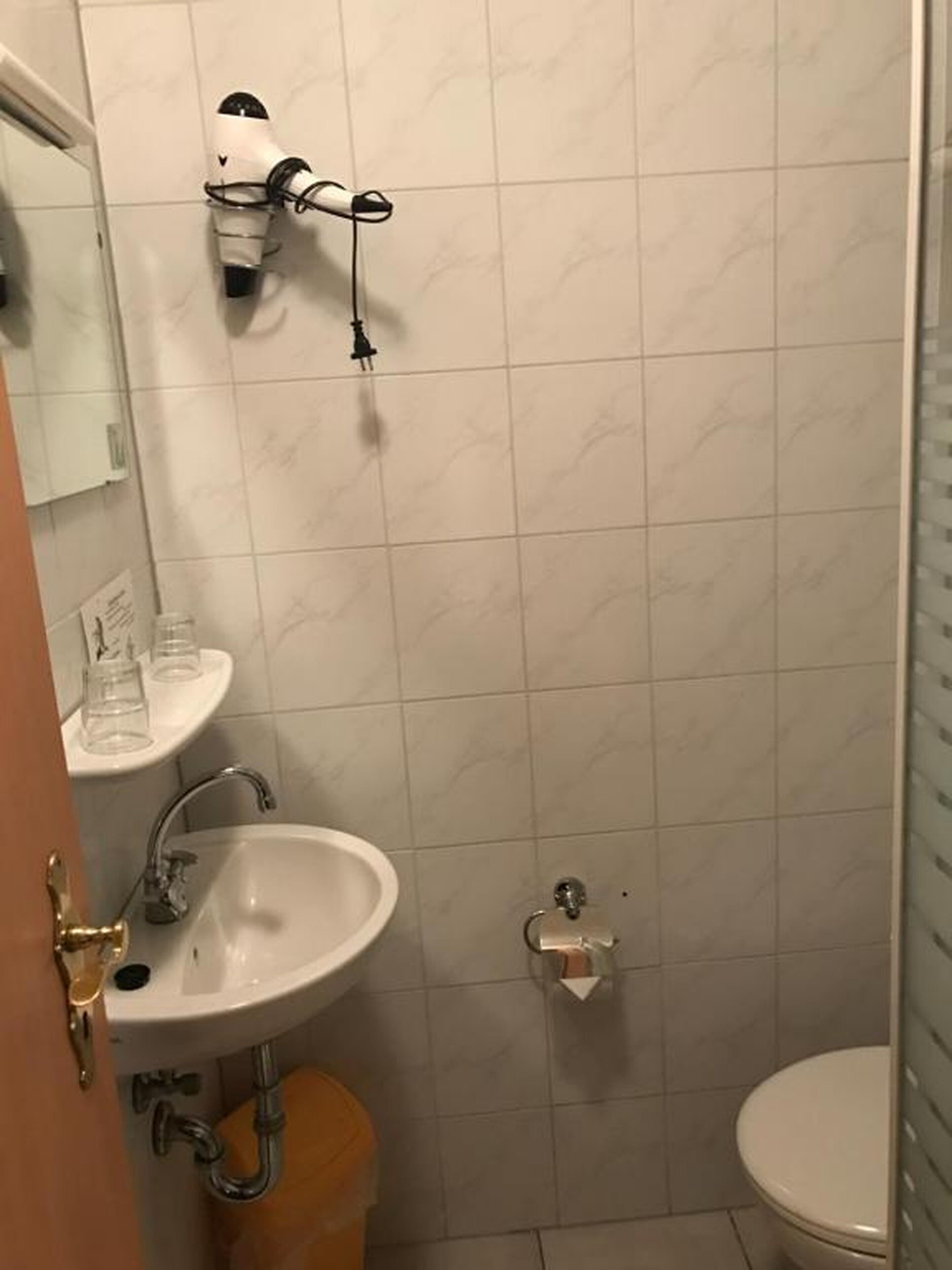 A bathroom with a sink, mirror, and a hairdryer mounted on the wall.