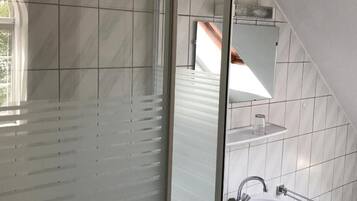 A modern bathroom with a shower, a sink, and a large mirror.