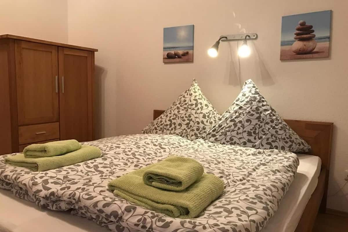 A neatly made bed with patterned bedding and two folded towels.