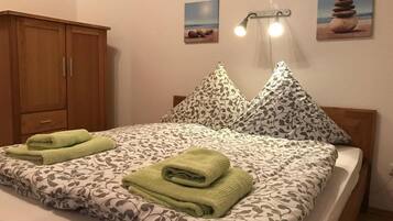 A neatly made bed with patterned bedding and two folded towels.
