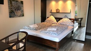 Una cama ordenada con ropa de cama estampada, un cabecero de madera y una mesita de noche con una lámpara.
