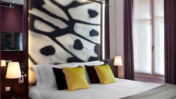 Habitación de hotel con una cama grande, dos lámparas de noche, un televisor en la pared y un ventanal con cortinas.