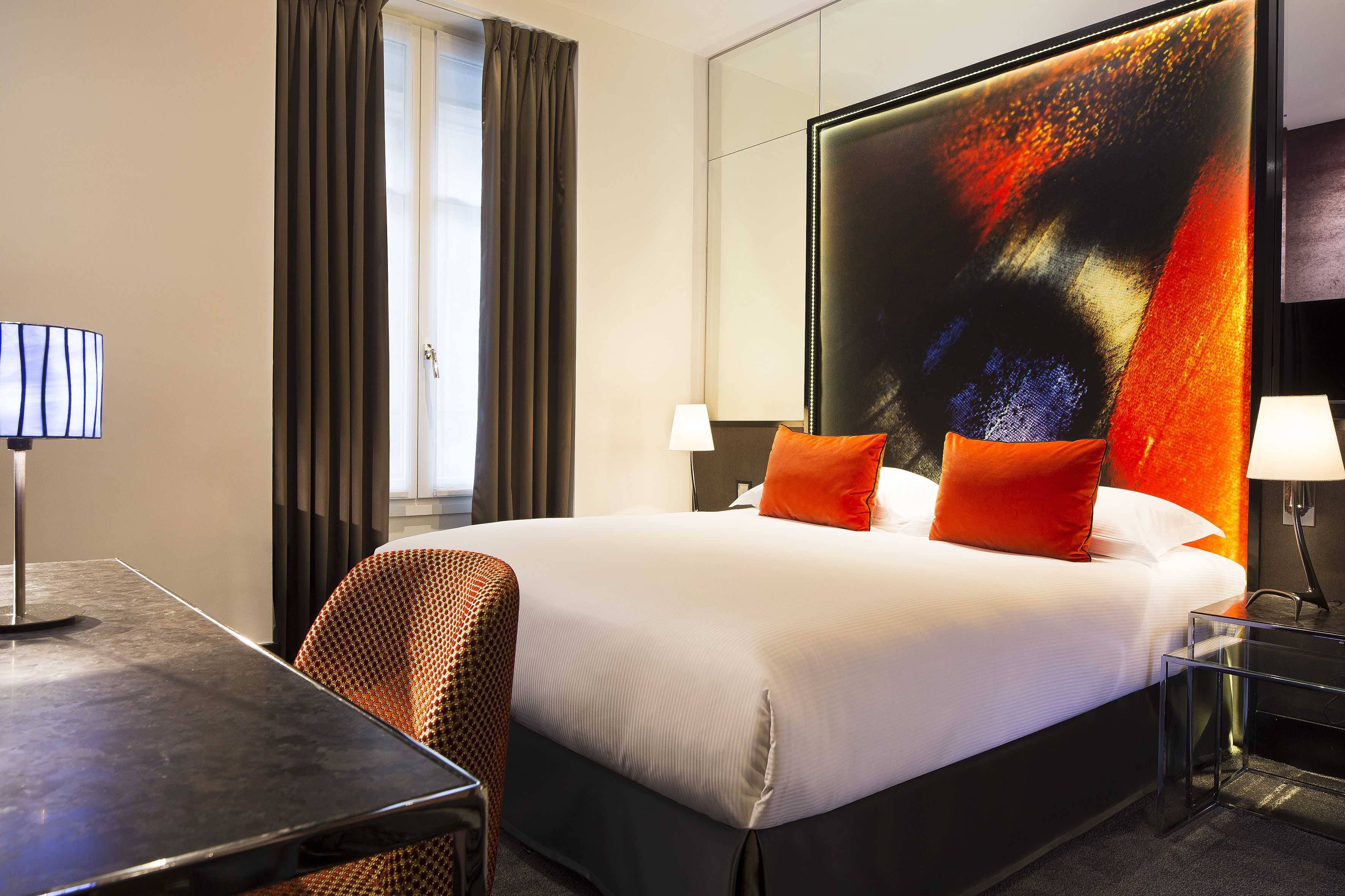 Quarto de hotel moderno com uma cama grande, uma escrivaninha e uma cadeira.