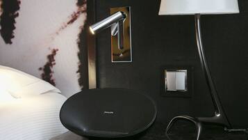 Een moderne badkamer met een zwarte wastafel, een spiegel, een wandlamp en een witte bedlamp.