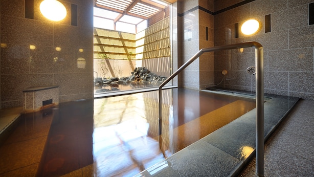 A modern indoor pool area with a glass wall, metal railings, and a stone floor. - Route-Inn Grantia Shiretoko Shariekimae (Shari)