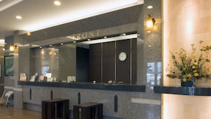 A reception desk with a "FRONT" sign, a clock, and a vase with flowers. - Route-Inn Grantia Shiretoko Shariekimae (Shari)