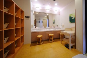 Un baño con un espejo grande, dos lavamanos, cestas de mimbre en estantes y suelo de madera.