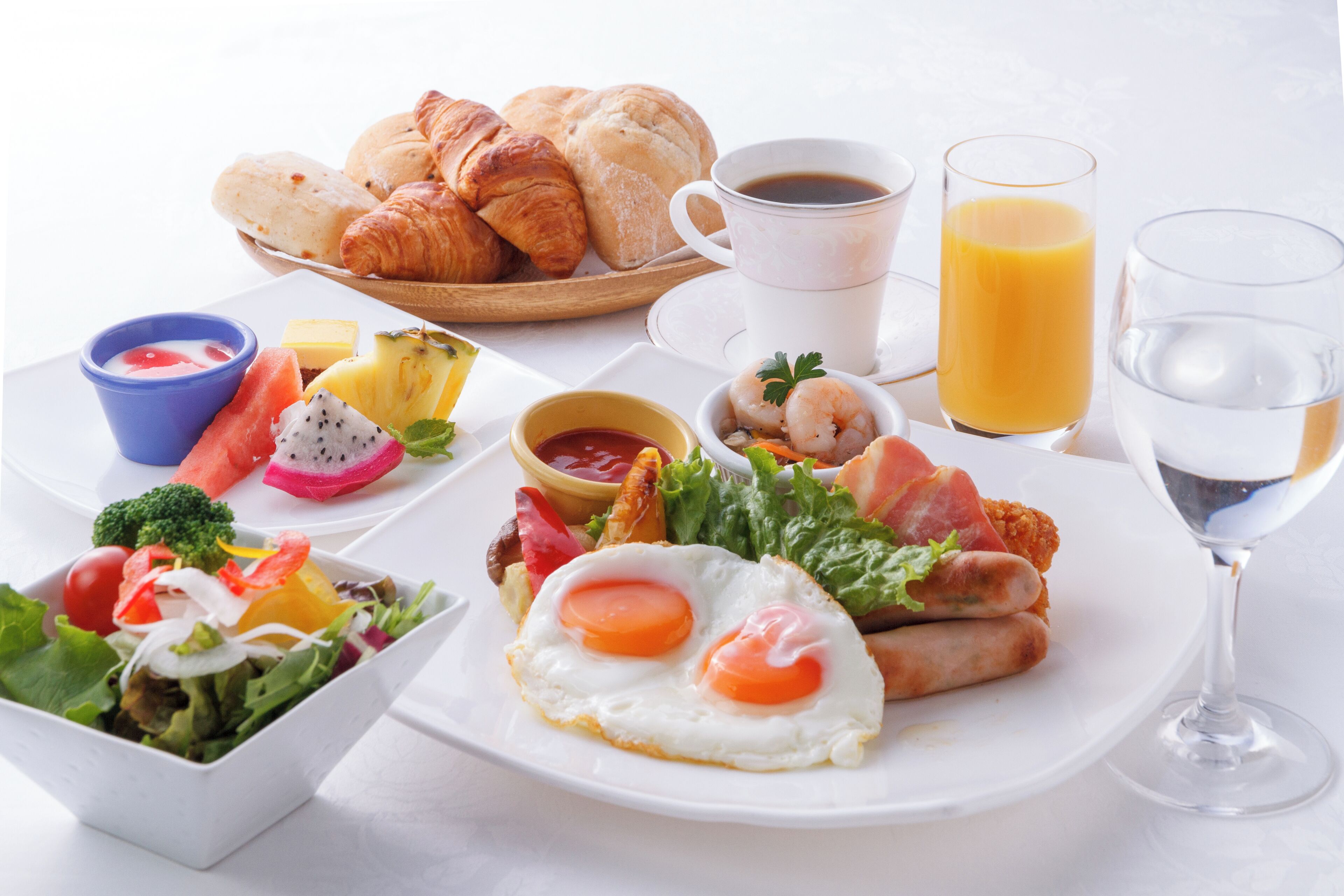A breakfast plate with eggs, sausages, bacon, and a salad.
