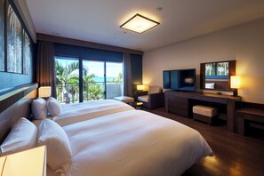 Una habitación de hotel con una cama grande, un escritorio con televisor y un balcón con vistas a palmeras.