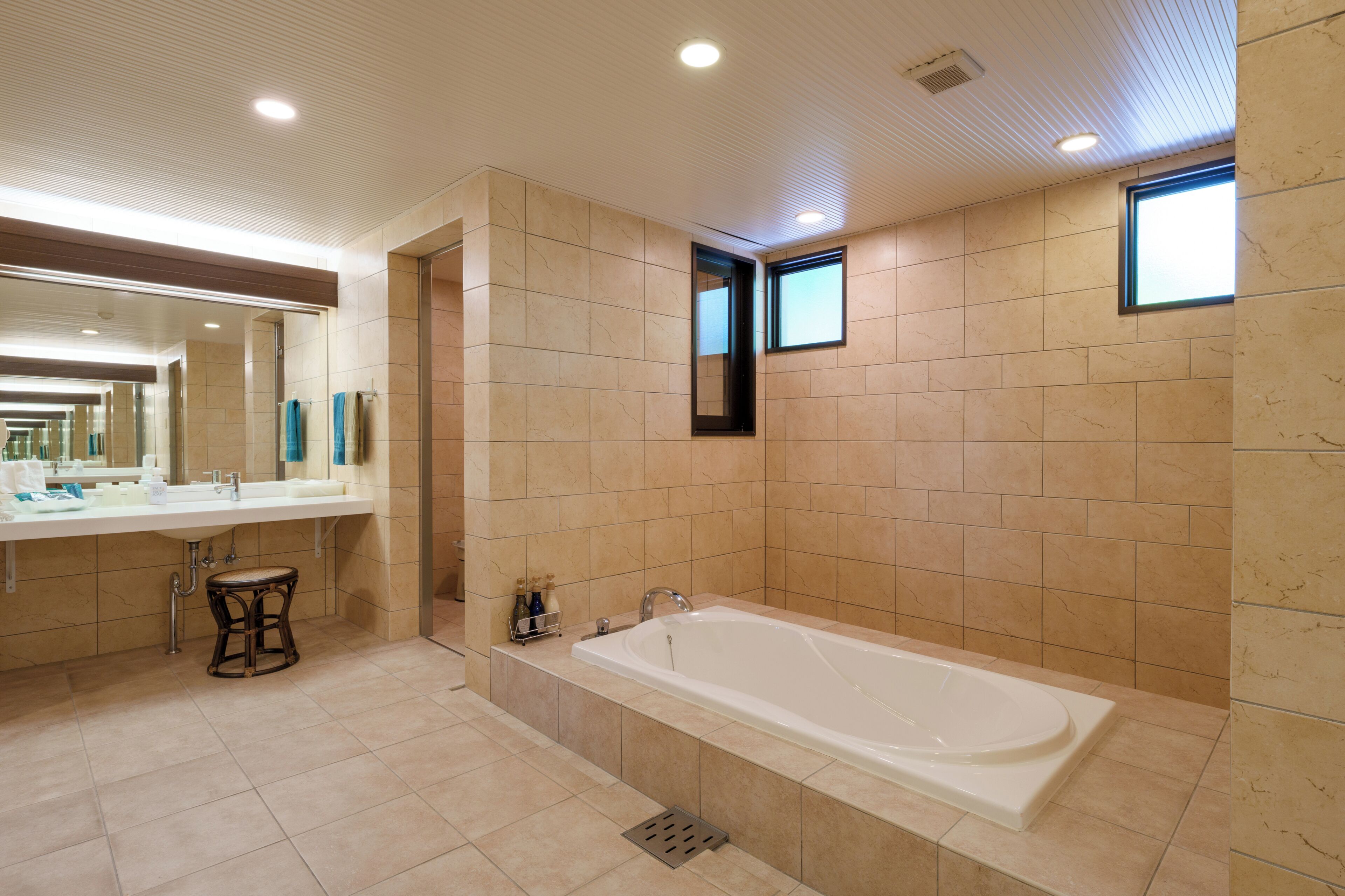 Un baño moderno con una bañera grande, un tocador con espejo y un taburete.