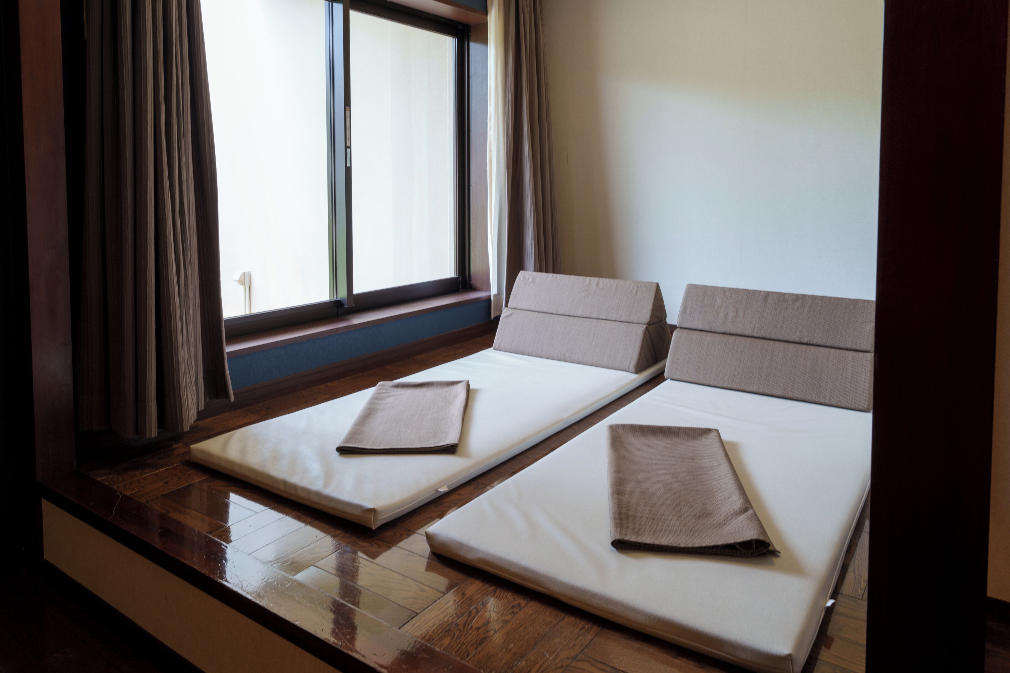 Ein Zimmer mit zwei Betten, einem Vorhangfenster und Holzboden.