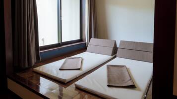 Une chambre avec deux lits, une fenêtre avec des rideaux et un plancher en bois.