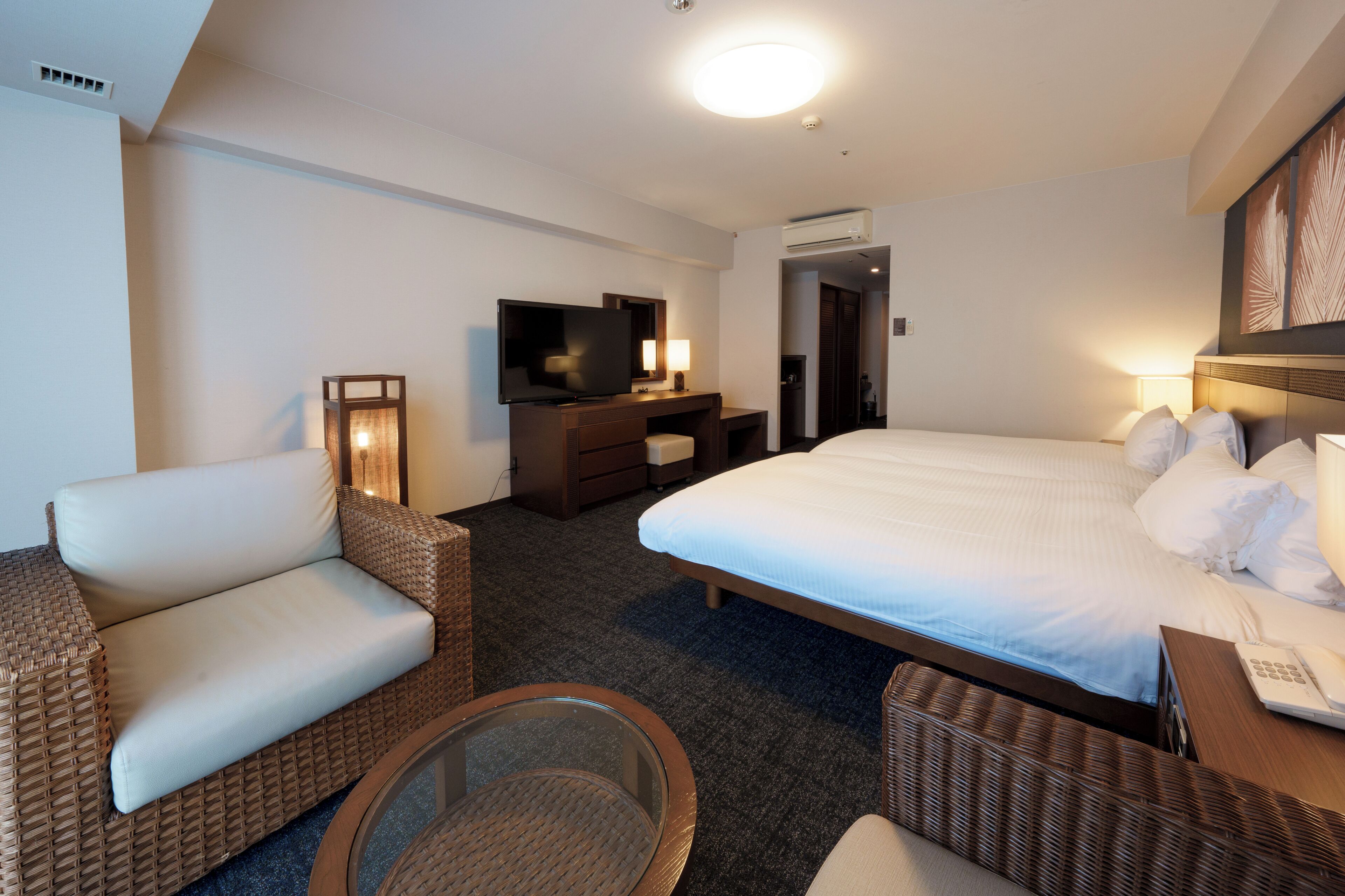 A hotel room with a bed, a television, a desk, a chair, and a small table.