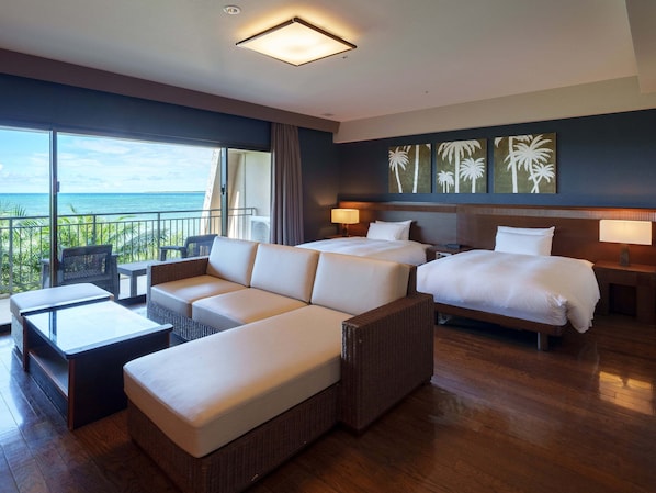 Une chambre d’hôtel avec un grand lit, un canapé, une petite table et un balcon donnant sur l’océan.