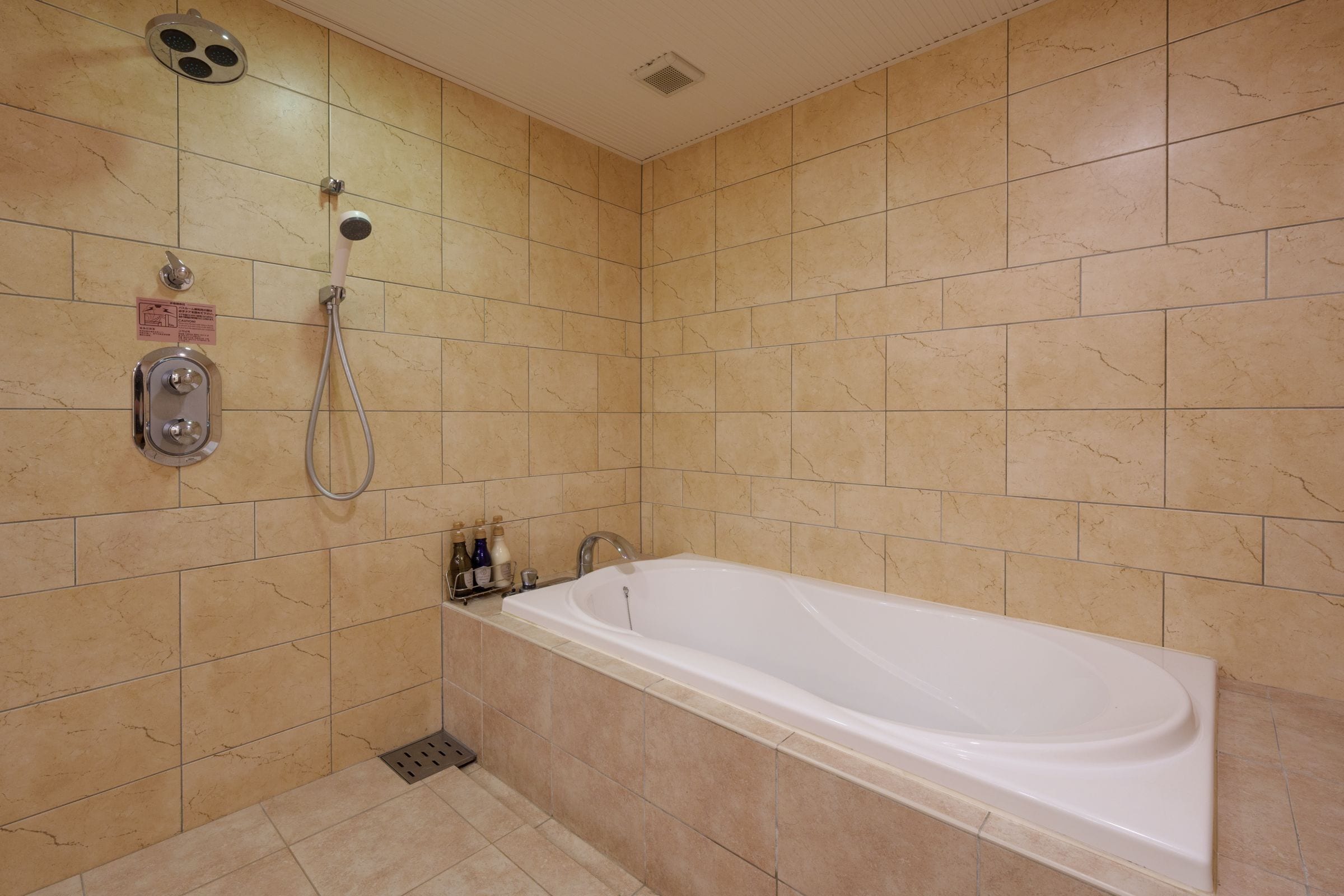 A bathroom with a bathtub, a shower, and a hand dryer.