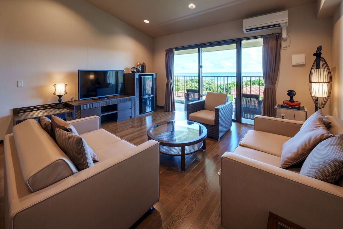 Un salon moderne comprenant un canapé, un téléviseur, une petite table et un balcon avec vue.