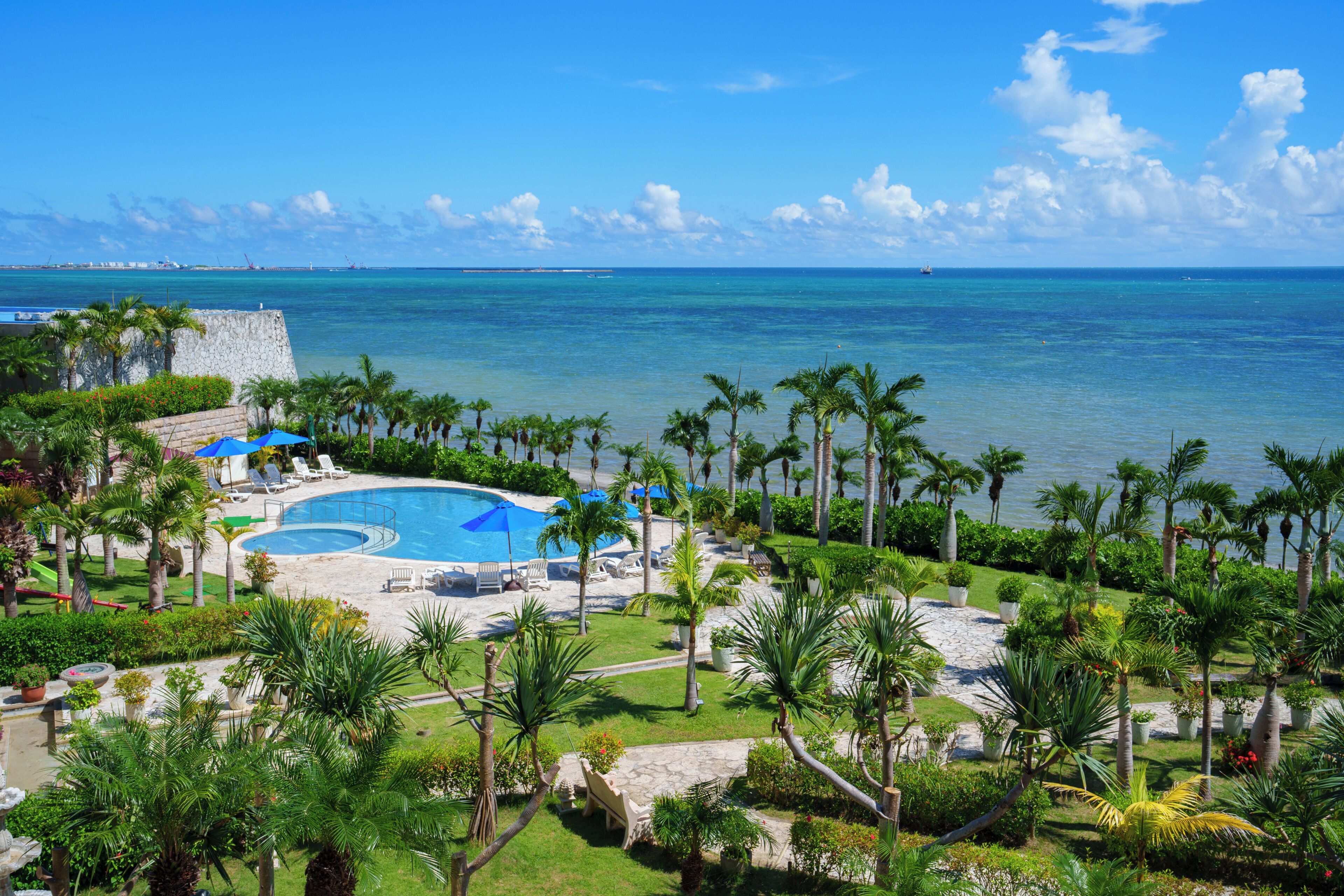 Un resort con piscina, sillas de descanso y palmeras.