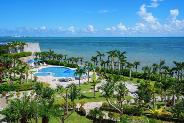 Un resort con piscina, sillas de descanso y palmeras.